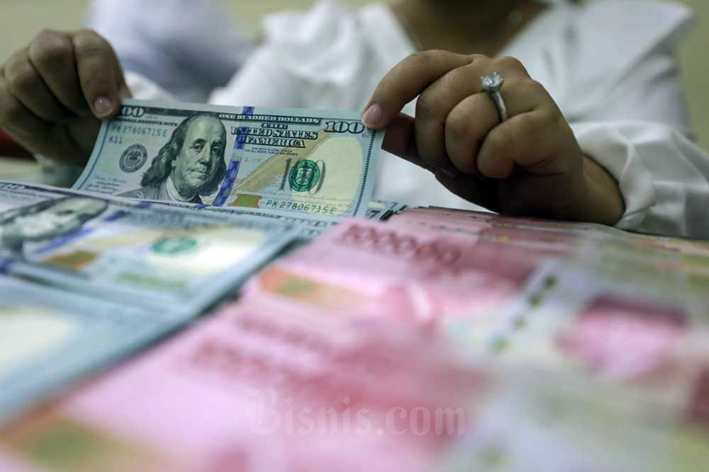 Pegawai menunjukan mata uang rupiah dan dolar Amerika Serikat di Dolar Asia Money Changer, Jakarta. Bisnis/Himawan L Nugraha