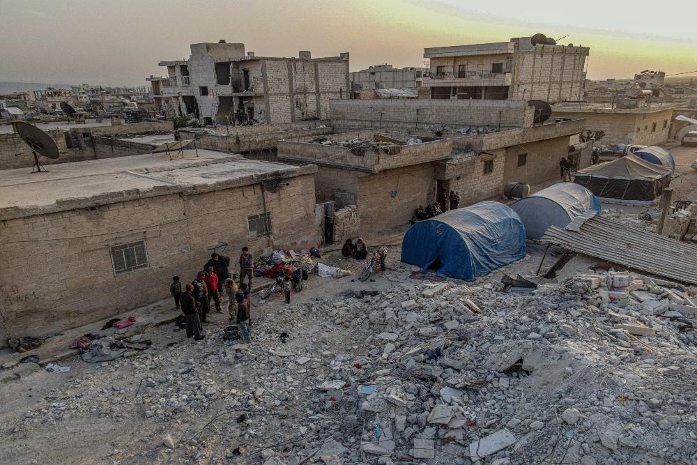 Sejumlah warga di Kota Jenderes di pedesaan Aleppo, barat laut Suriah, pada 27 Februari 2023, mencari barang-barang mereka yang terkubur di antara reruntuhan rumah mereka yang hancur akibat gempa dahsyat, sementara yang lain duduk di atas puing-puing/Reutersrnrn