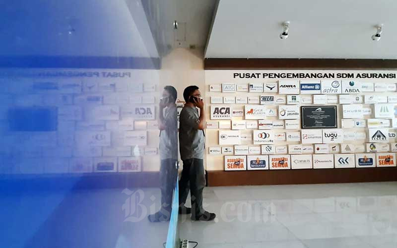 Karyawan beraktifitas di dekat deretan logo-logo perusahaan asuransi di Kantor Asosiasi Asuransi Umum Indonesia (AAUI) di Jakarta, Selasa (22/9/2020). Bisnis/Himawan L Nugraha