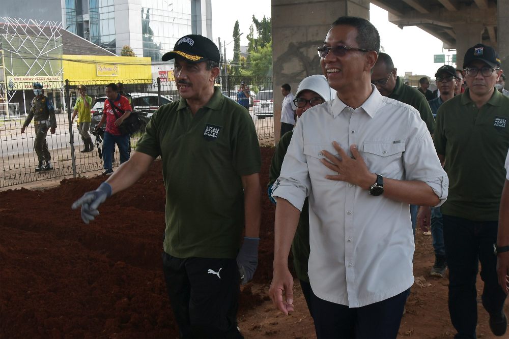 Penjabat Gubernur DKI Jakarta Heru Budi Hartono (kanan) bersama Wali Kota Jakarta Timur M Anwar (kiri) saat meninjau penataan kawasan hijau di bawah kolong Tol Becakayu (Bekasi Cawang Kampung Melayu), Jakarta, Jumat (6/1/2023). Kegiatan tersebut untuk memastikan penataan kawasan hijau yang telah dikerjakan sepanjang 2,7 km dari target 5 km di Jakarta terus berjalan sehingga bisa memberi kenyamanan serta kesegaran bagi warga. ANTARA FOTO/Fakhri Hermansyah/nym.