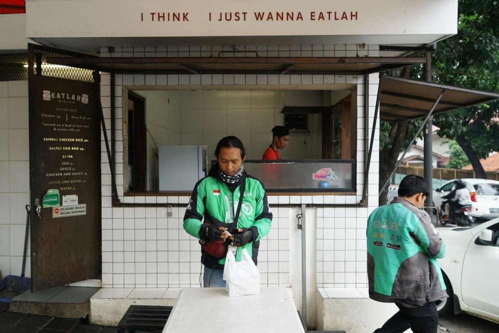 Seorang kurir Go-Food, layanan pesan-antar makanan yang dioperasikan oleh PT GoTo Gojek Tokopedia Tbk (GOTO), sedang mengambil pesanan pelanggan di Jakarta, Indonesia. - Bloomberg/Dimas Ardian