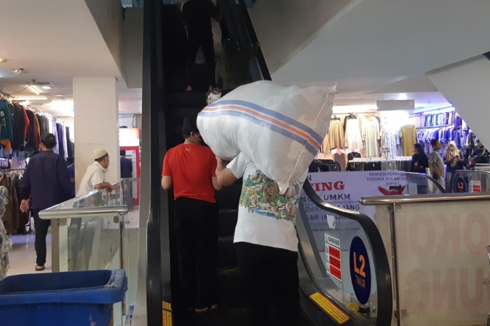 Pedagang pakaian bekas di lantai 2 Pasar Senen Blok III mengangkut stok ballpress dari toko tempat penyimpanan. /Bisnis-Widya Islamiati.