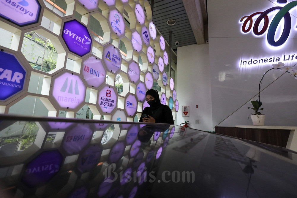 Karyawati beraktivitas di dekat logo-logo perusahaan asuransi di kantor Asosiasi Asuransi Jiwa Indonesia (AAJI) di Jakarta./ Bisnis/Arief Hermawan P