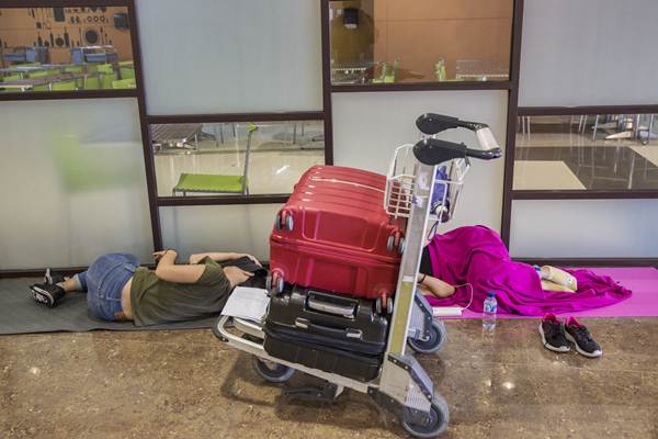 Wisatawan mancanegara tidur menunggu keberangkatan pesawat, di bandara Internasional Ngurah Rai, Bali./Bloomberg-Putu Sayoga