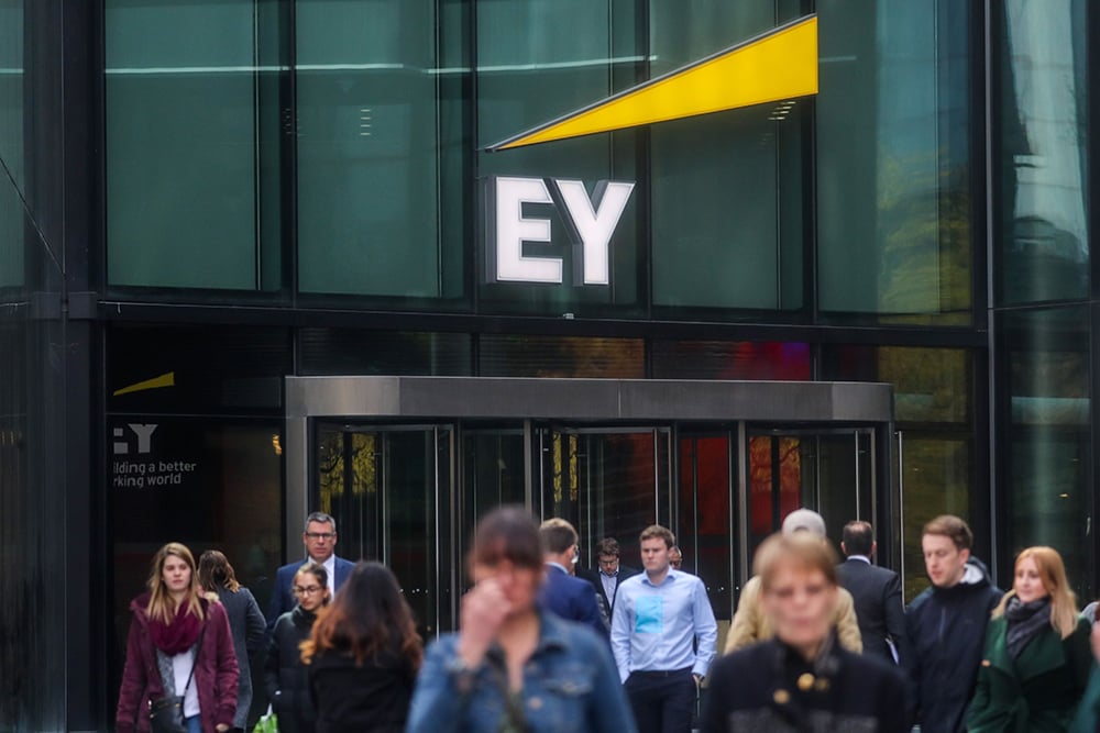 Pejalan kaki berjalan di depan logo Ernst & Young di London, UK. /Bloomberg-Simon Dawson