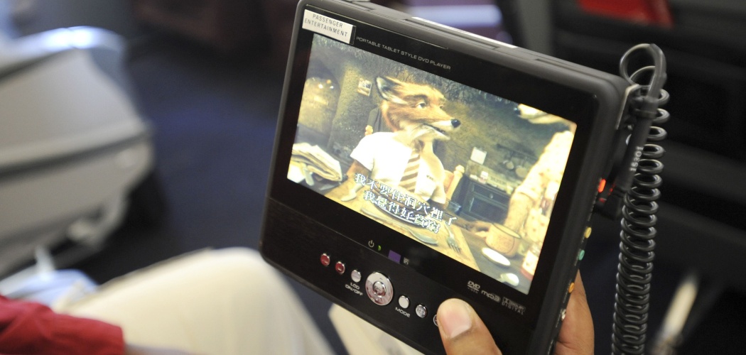 Seorang penumpang menonton film menggunakan DVD player portabel di pesawat Delta Air Lines Inc. di Hartsfield-Jackson Atlanta International Airport di Atlanta, AS, Jumat (17/12/2010)./Bloomberg-Erik S. Lesser