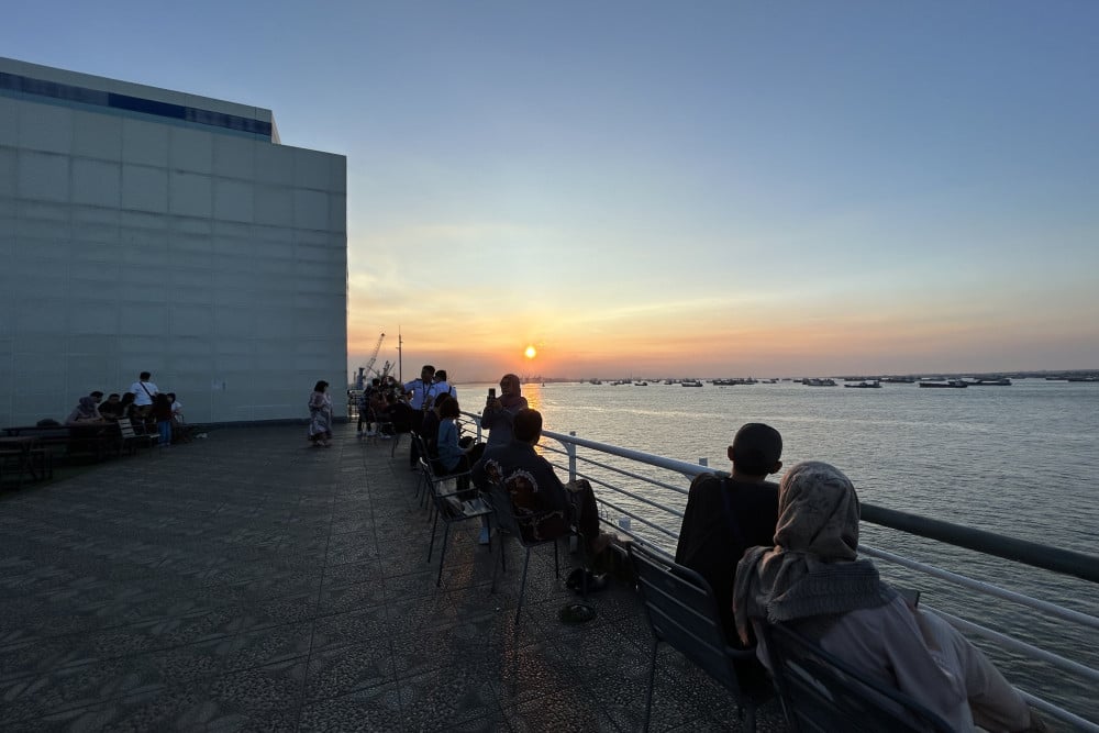Sejumlah pengunjung menyaksikan matahari terbenam dan kapal yang berlayar di sekitar perairan Pelabuhan Tanjung Perak, Surabaya, Jawa Timur, Rabu (19/4). Bisnis/Arief Hermawan P