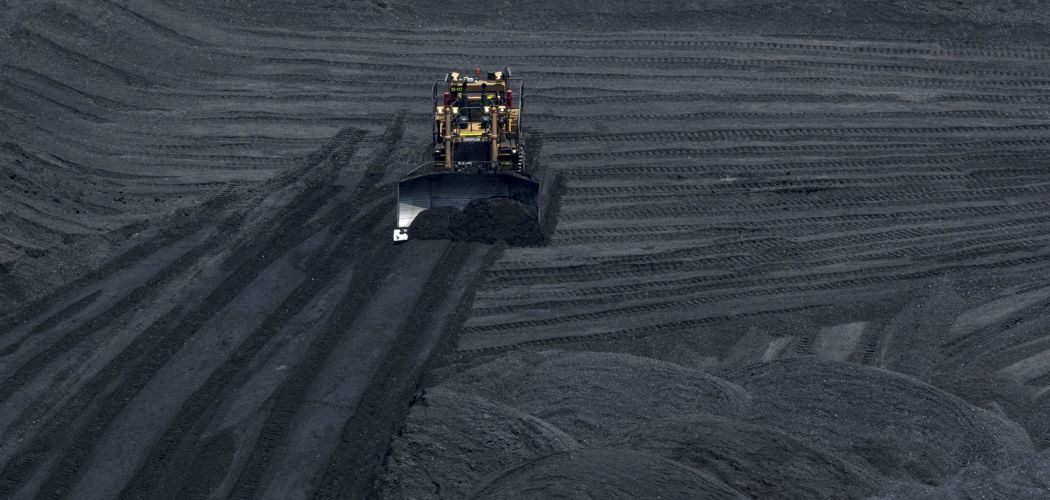 Alat berat membersihkan area penimbunan batu bara./ Bloomberg - Nicolo Filippo Rosso. Masihkah Ada Napas untuk Ekspor Batu Bara ke China?