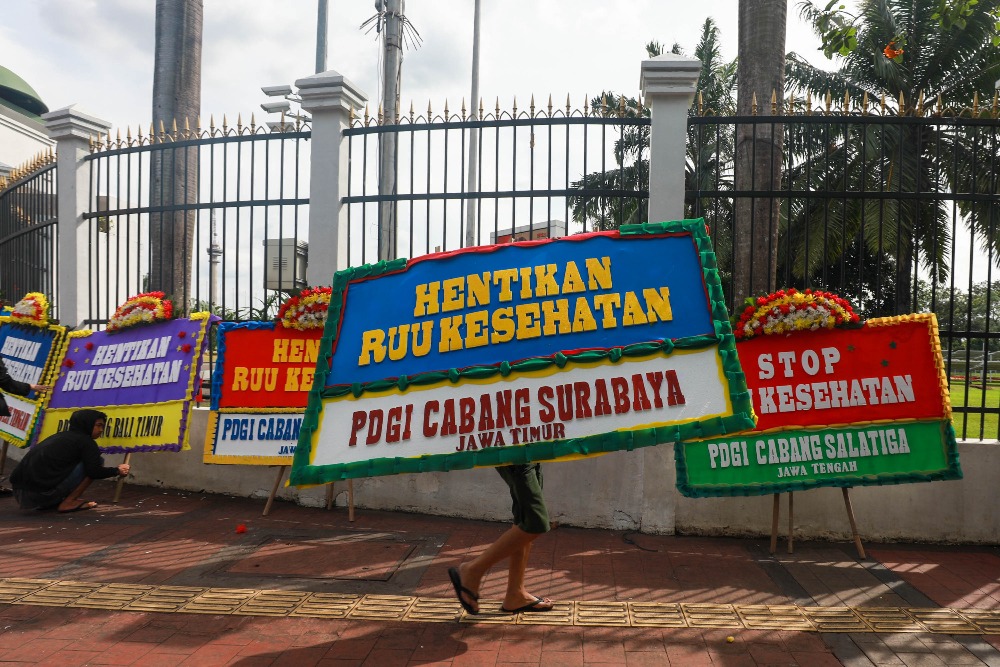 KARANGAN BUNGA PENOLAKAN RUU KESEHATAN Pekerja memasang karangan bunga berisi penolakan RUU Kesehatan di Kompleks DPR, Jakarta, Kamis (13/4/2023). JIBI/Bisnis/Himawan L Nugraha