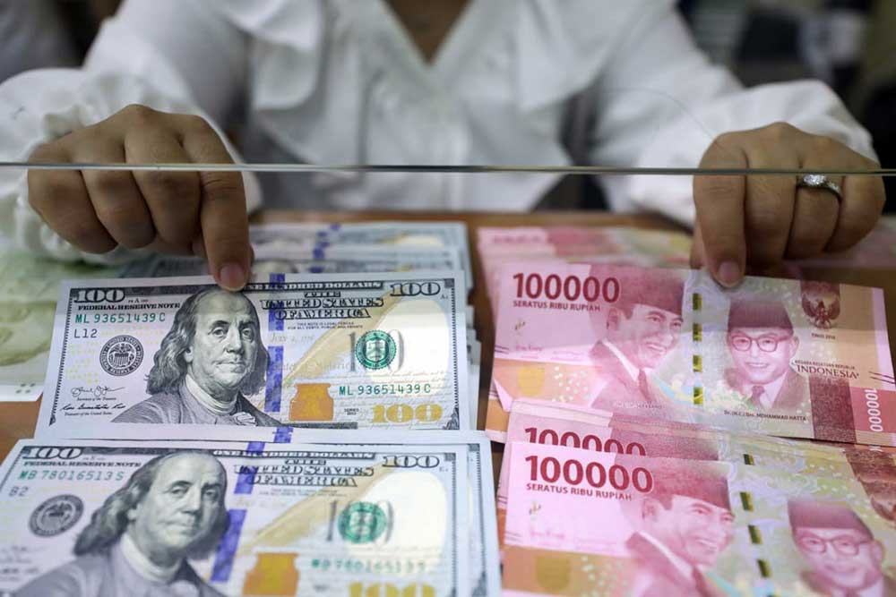 Pegawai menunjukan mata uang rupiah dan dolar Amerika Serikat di Dolar Asia Money Changer, Jakarta, Senin (18/7/2022). Bisnis/Himawan L Nugraha