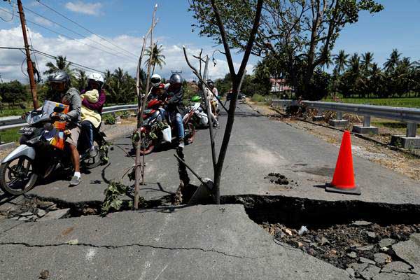 Warga mengendarai sepeda motor menghindari jalan yang rusak akibat gempa, di Lombok Utara, NTB, Selasa (7/8/2018)./Reuters-Beawiharta