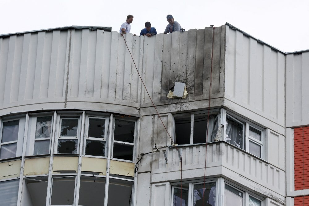 Pria terlihat di atap blok apartemen bertingkat yang rusak menyusul serangan drone yang dilaporkan di Moskow, Rusia, 30 Mei 2023. REUTERS/Maxim Shemetov