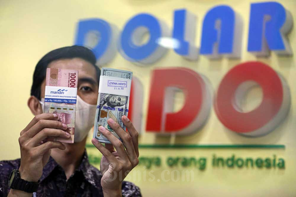 Karyawan memperlihatkan uang rupiah dan dolar AS di gerai penukaran mata uang asing Dolarindo di Jakarta, Rabu (6/72022). Bisnis/Arief Hermawan P