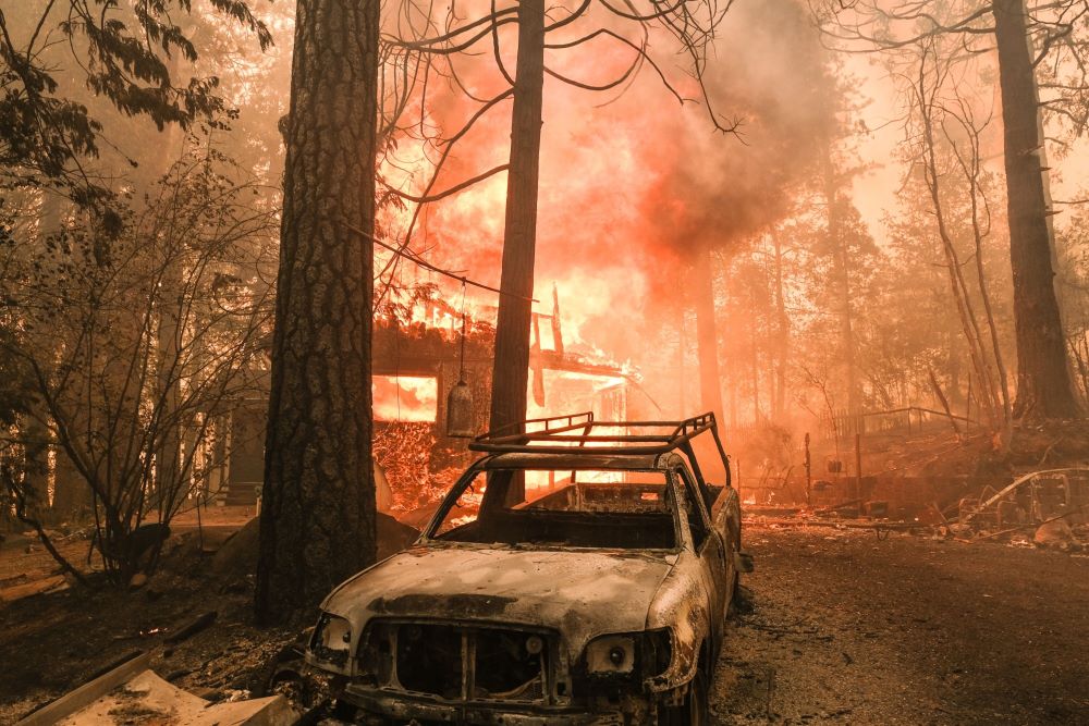 Bangunan terbakar di belakang kendaraan yang hangus di jalan Jerseydale selama Kebakaran Hutan Oak di Mariposa County, California, AS, 23 Juli 2022. /Bloomberg