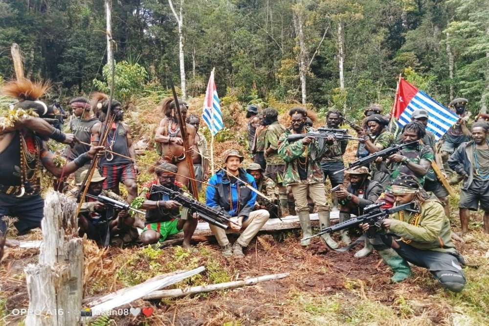 Seorang pria yang diidentifikasi sebagai Philip Mehrtens, pilot Selandia Baru yang disebut-sebut disandera oleh kelompok pro-kemerdekaan, duduk di antara para pejuang separatis di wilayah Papua Indonesia, 6 Maret 2023. Tentara Pembebasan Nasional Papua Barat (TPNPB) )/Handout melalui REUTERS/File Foto