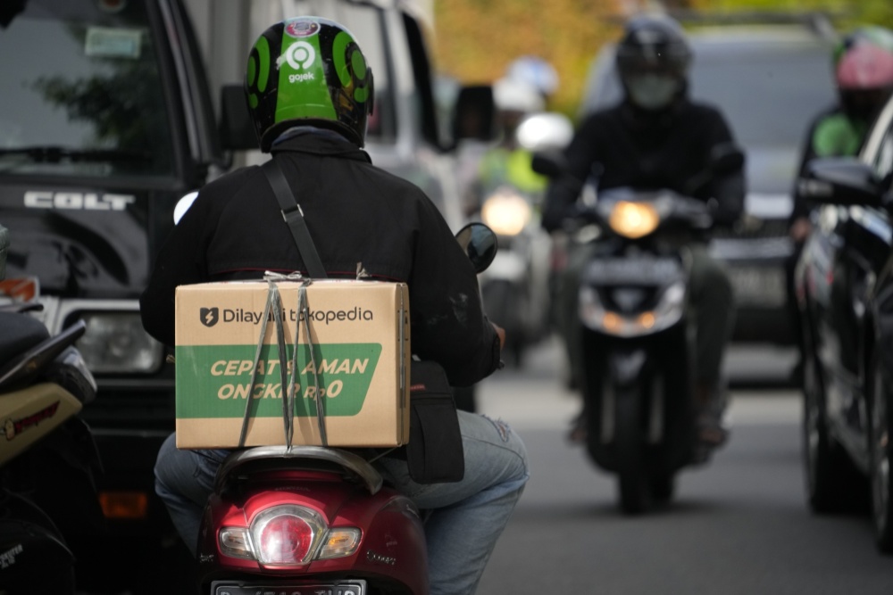 Seorang pengemudi Gojek mengantarkan pesanan Tokopedia di Jakarta, Indonesia, pada Jumat, 8 April 2022. Gojek dan Tokopedia merupakan layanan milik PT Goto Gojek Tokopedia Tbk (GOTO). / Dimas Ardian-Bloomberg