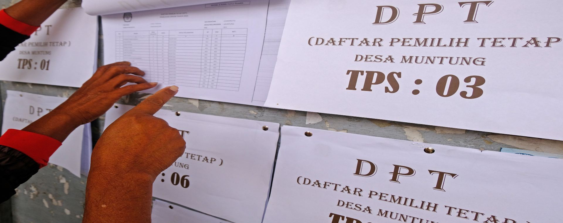 Warga mencari namanya pada papan pengumuman daftar pemilih tetap (DPT)./Antara-Anis Efizudin.