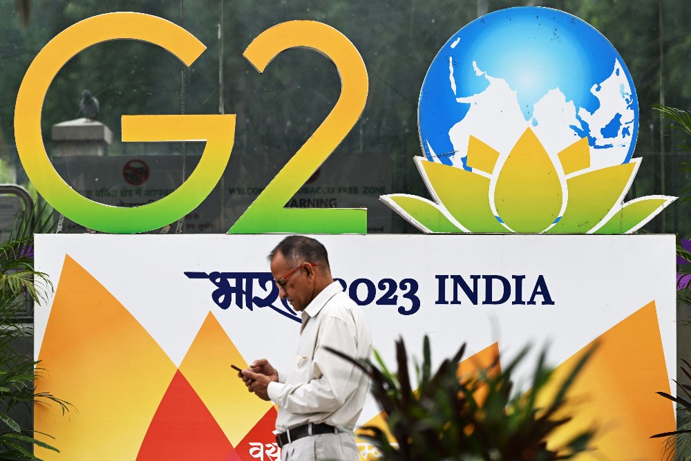 Seorang warga melintas di poster KTT G20 yang akan digelar di New Delhi, India pada 9-10 September 2023./ Bloomberg