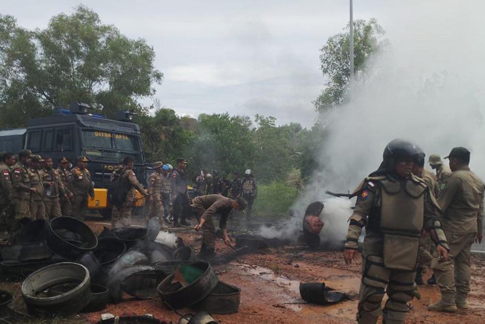 Petugas gabungan membersihkan tumpukan ban yang dibakar warga di lokasi bentrokan di Pulau Rempang./ ANTARA - Yude