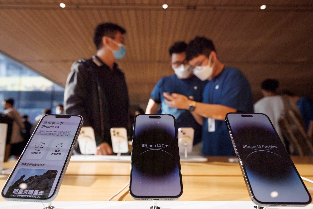 Seorang pelanggan berbicara dengan asisten penjualan di toko Apple saat model iPhone 14 baru Apple Inc mulai dijual di Beijing, Tiongkok, 16 September 2022. / REUTERS-Thomas Peter