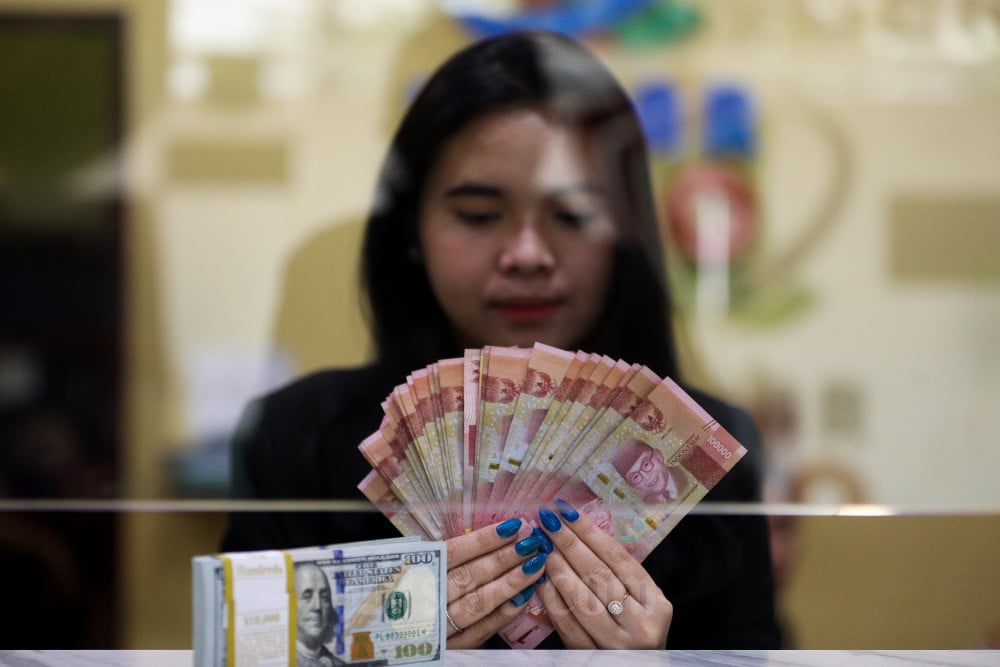 Karyawati menghitung mata uang rupiah dan dolar Amerika Serikat di tempat penukaran uang asing di Jakarta, Senin (14/8/2023). Bisnis/Suselo Jati