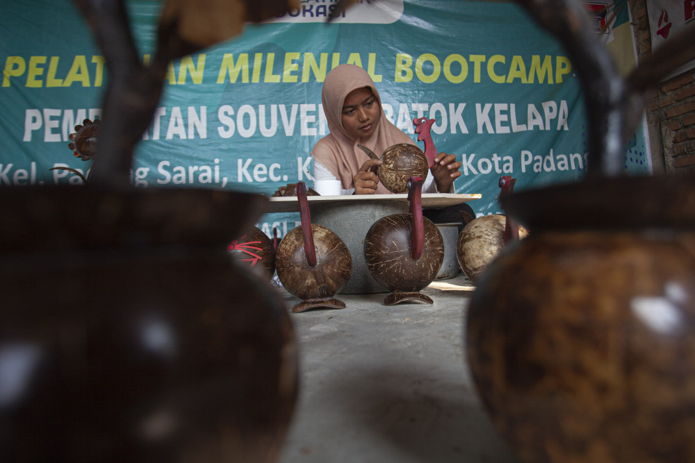 Perajin batok kepala, Nesa, 23, membuat celengan yang dirakit dari batok kelapa di rumah produksi, Kota Padang, Sumatra Barat./Bisnis-Muhammad Noli Hendra