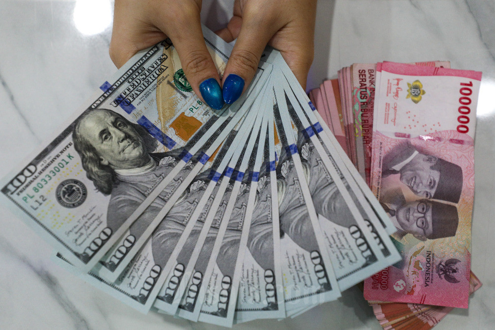 Karyawati menghitung mata uang rupiah dan dolar Amerika Serikat di tempat penukaran uang asing di Jakarta, Senin (14/8/2023). Bisnis/Suselo Jati
