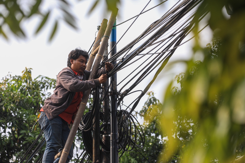 Petugas merapihkan jarigan kabel milik Indihome di Jakarta/JIBI/Bisnis/Abdurachman.