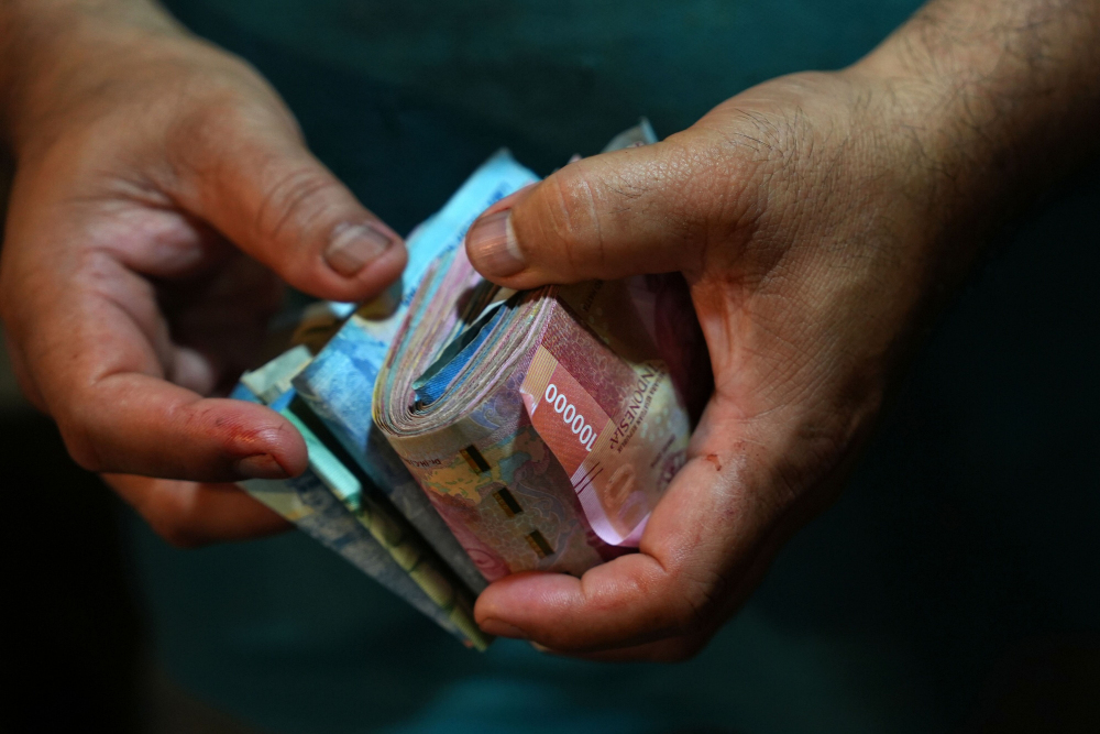 Warga memegang sejumlah uang rupiah di Pasar Petisah, Medan, Sumatra Utara pada Minggu (29/1/2023). - Bloomberg/Dimas Ardian