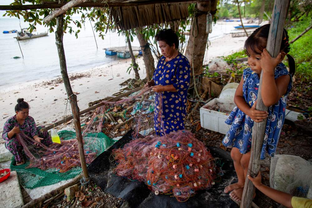 Dua warga memperbaiki jaring ikan di perkampungan nelayan Sembulang, Pulau Rempang, Batam, Kepulauan Riau, Minggu (17/9/2023). Sejak dua pekan terakhir nelayan di pulau tersebut tidak melaut dampak dari rencana relokasi warga untuk proyek strategis nasional (PSN) Rempang Eco-City Pulau Rempang. ANTARA FOTO/Teguh Prihatna/YU