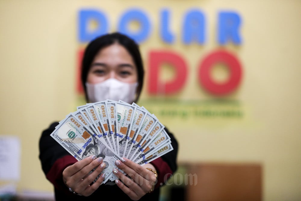Karyawati menunjukkan mata uang Dolar Amerika Serikat di tempat penukaran uang asing di Jakarta, Rabu (30/8/2023). Bisnis/Suselo Jati