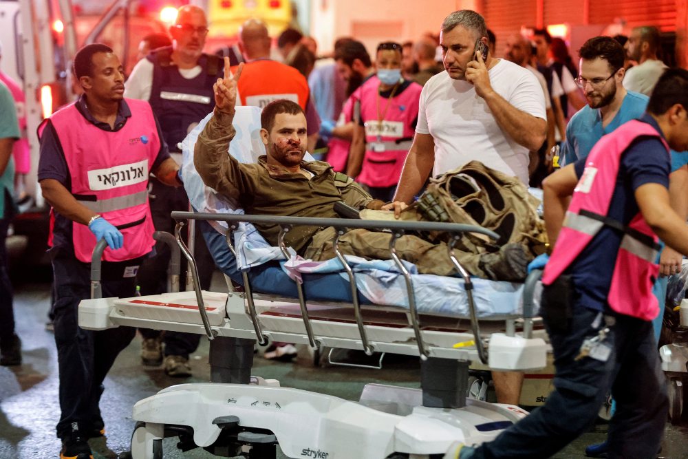 Seorang petugas Israel yang terluka memberi isyarat ketika dia tiba di rumah sakit, menyusul infiltrasi massal oleh orang-orang bersenjata Hamas dari Jalur Gaza, di Ashkelon, Israel selatan 7 Oktober 2023. REUTERS/Amir Cohenrn