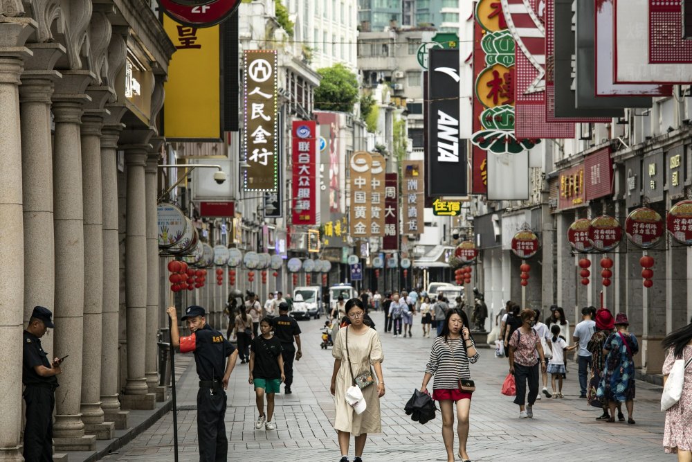 Pejalan kaki melintasi toko-toko di Guangzhou, China, Jumat, (11/8/ 2023). Bloomberg/qilai Shen