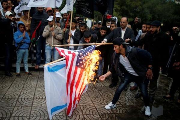 Warga Palestina membakar bendera Israel dan Amerika Serikat dalam sebuah demonstrasi terhadap niat Amerika Serikat memindahkan kedubes mereka ke Yerusalem dan mengenali Yerusalem sebagai ibukota Israel, di Kota Gaza, Rabu (6/12/2017). /Reuters