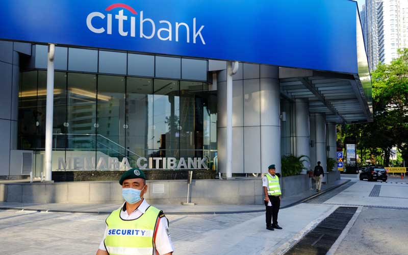 Pertugas keamanan menggunakan masker di luar cabang Citigroup Inc. Citibank di Kuala Lumpur, Malaysia, Selasa (17/3/2020). Citibank mengumumkan melepas bisnis konsumernya di luar Amerika Serikat. Di Indonesia, pembeli lini ini adalah UOB Indonesia yang sahamnya dimiliki oleh Singapura. Bloomberg/Samsul Said