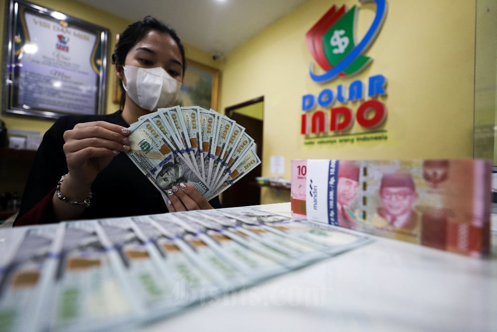 Karyawati menunjukkan mata uang Dolar Amerika Serikat di tempat penukaran uang asing di Jakarta, Rabu (30/8/2023). Bisnis/Suselo Jati