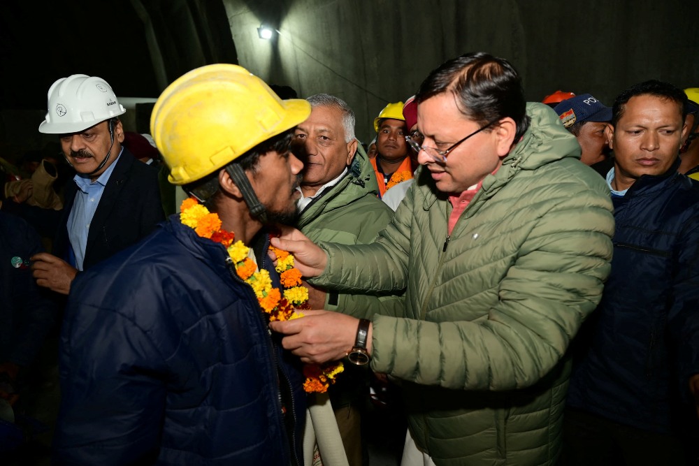 Pushkar Singh Dhami, Ketua Menteri Negara Bagian Utara Uttarakhand, menyapa seorang pekerja setelah dia diselamatkan dari lokasi terowongan yang runtuh di Uttarkashi, Uttarakhand, India, 28 November 2023. Petugas Informasi/Handout Distrik Uttarkashi melalui REUTERS
