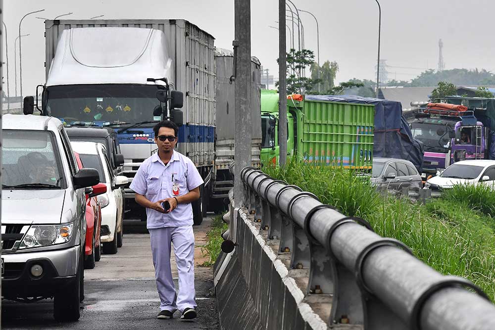Seorang pekerja berjalan kaki untuk menuju kawasan MM 2100 saat aksi buruh di  Kabupaten Bekasi, Jawa Barat, Kamis (30/11/2023). Aksi buruh yang menuntut kenaikan UMK (Upah Minimum Kabupaten/Kota) tersebut berdampak kemacetan kendaraan dari Tol Jakarta-Cikampek yang menuju kawasan industri MM 2100. ANTARA FOTO/ Fakhri Hermansyah