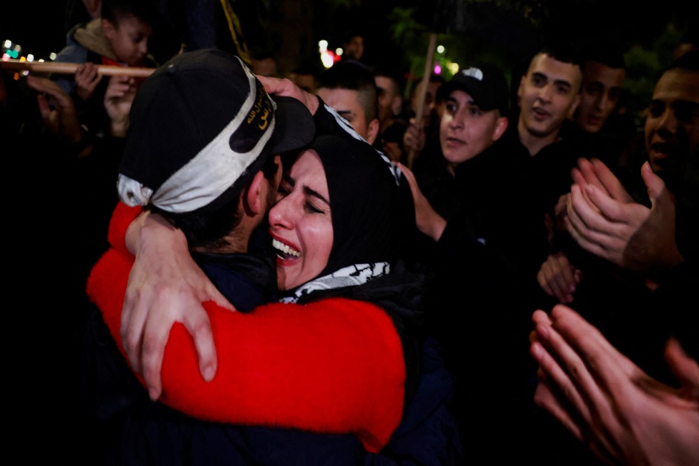Seorang tahanan Palestina memeluk ibunya setelah dibebaskan di tengah kesepakatan pertukaran sandera-tahanan antara Hamas dan Israel, di Ramallah, di Tepi Barat yang diduduki Israel, 1 Desember 2023. REUTERS/Ammar Awad