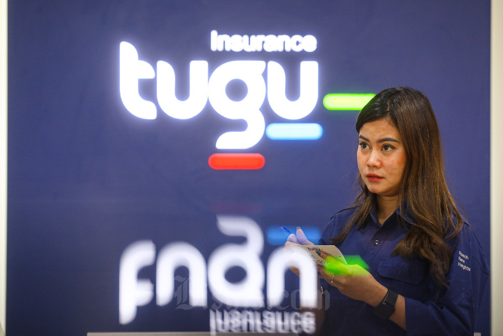 Karyawati beraktivitas di dekat logo Tugu Insurance, Jakarta, Senin (18/9/2023). Bisnis/Abdurachman