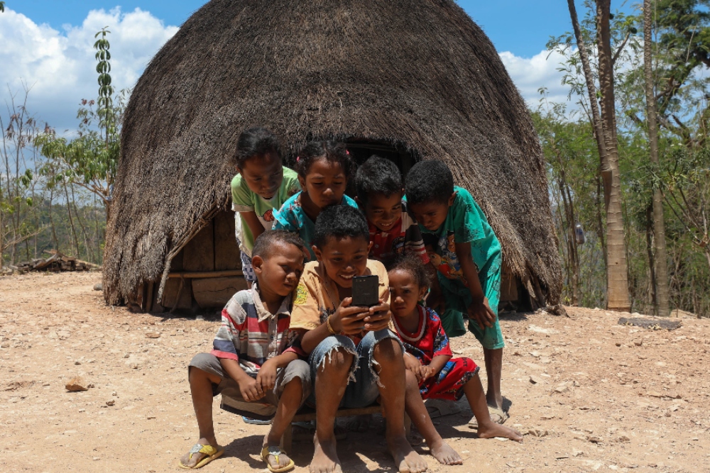 Anak-anak Suku Boti mengakses smartphone di depan Ume Kbubu atau rumah bulat di Desa Boti, Timor Tengah Selatan, Nusa Tenggara Timur (NTT), Minggu (26/11/2023). JIBI/Bisnis/Himawan L Nugraha