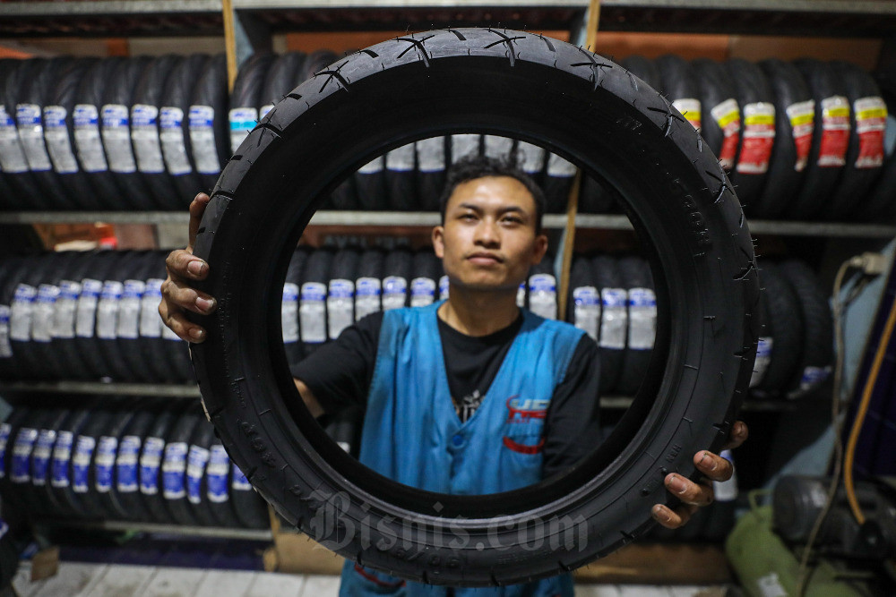 Pekerja menata ban sepeda motor bermerek IRC dan Zeneos yang diproduksi PT Gajah Tunggal Tbk. di salah satu gerai di Jakarta, Senin (7/8/2023). Bisnis/Arief Hermawan P