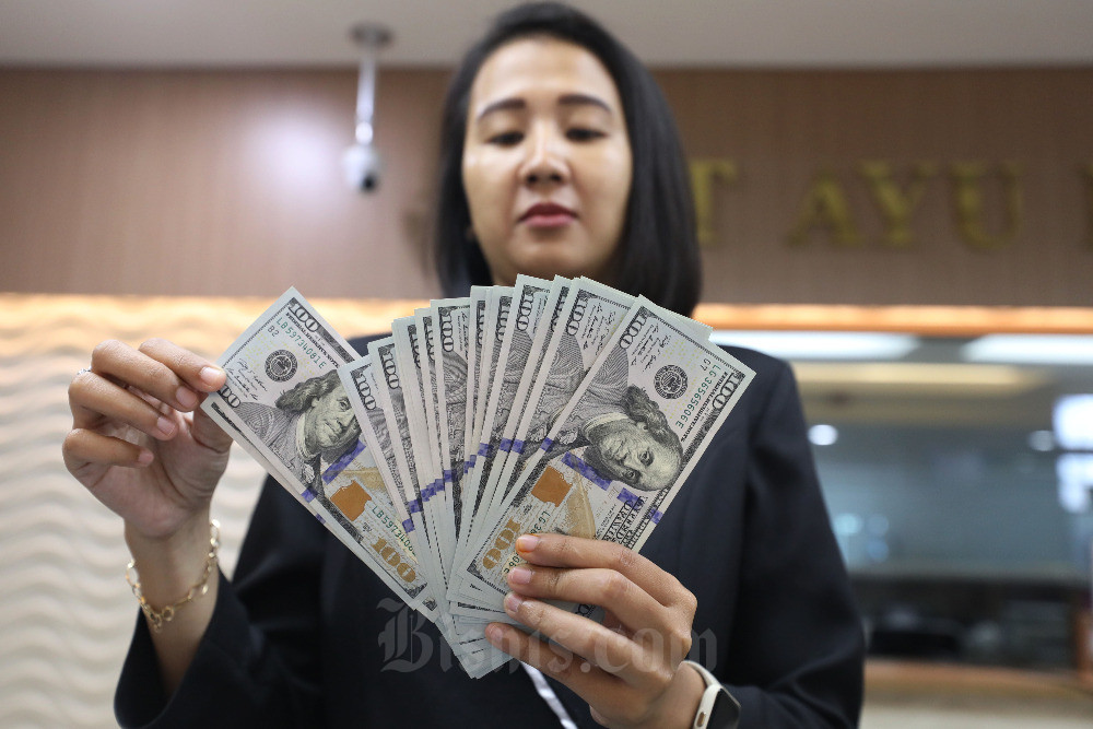 Karyawan menunjukan uang dolar Amerika Serikat (AS) di salah satu gerai penukaran mata uang asing di Jakarta, Rabu (23/8/2023). Bisnis/Eusebio Chrysnamurti
