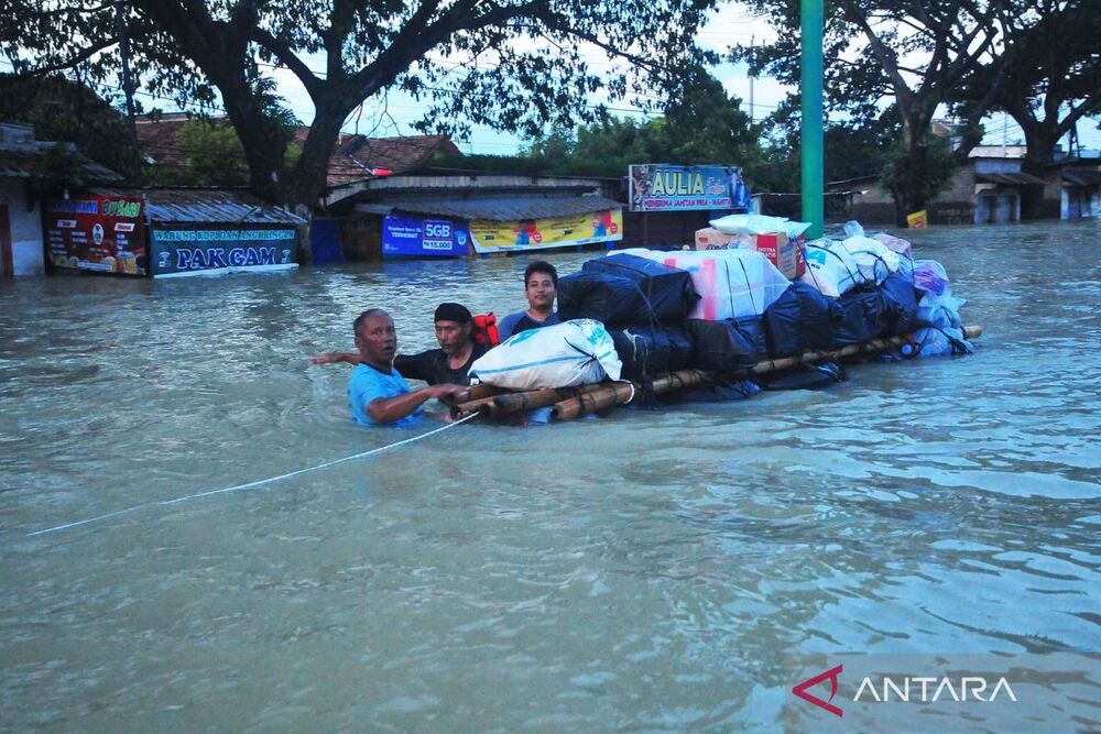 Warga korban banjir mengangkut sembako di jalan Pantura yang terendam banjir di Karanganyar, Demak, Jawa Tengah, Senin (12/2/2024)./Antara-Yusuf Nugroho.