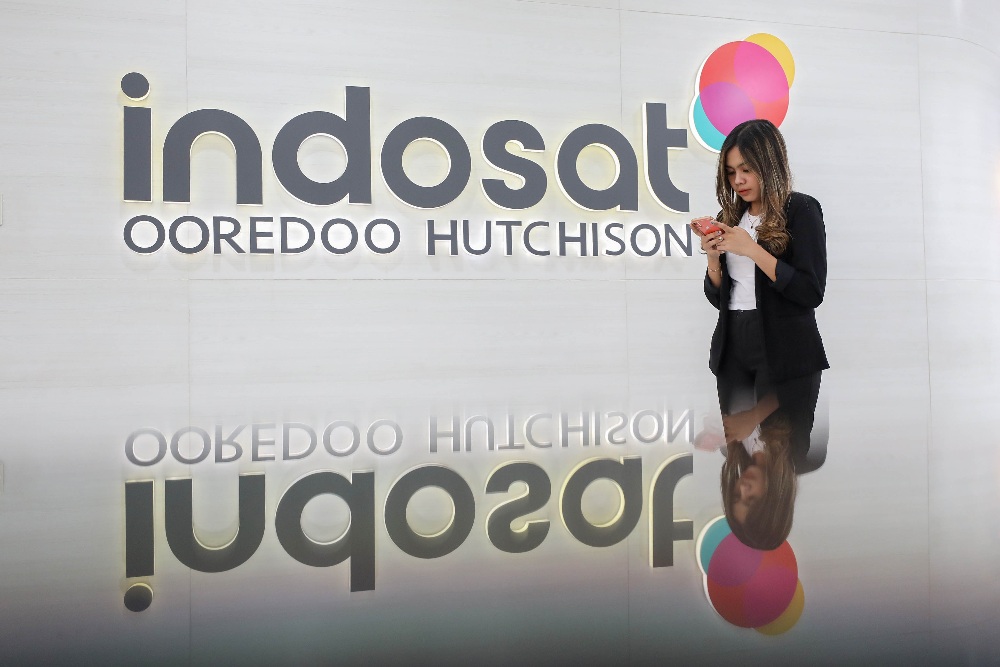 Karyawan beraktivitas di dekat logo Indosat Ooredoo Hutchison (IOH) di Jakarta, Senin (5/2/2024). JIBI/Bisnis/Eusebio Chrysnamurti