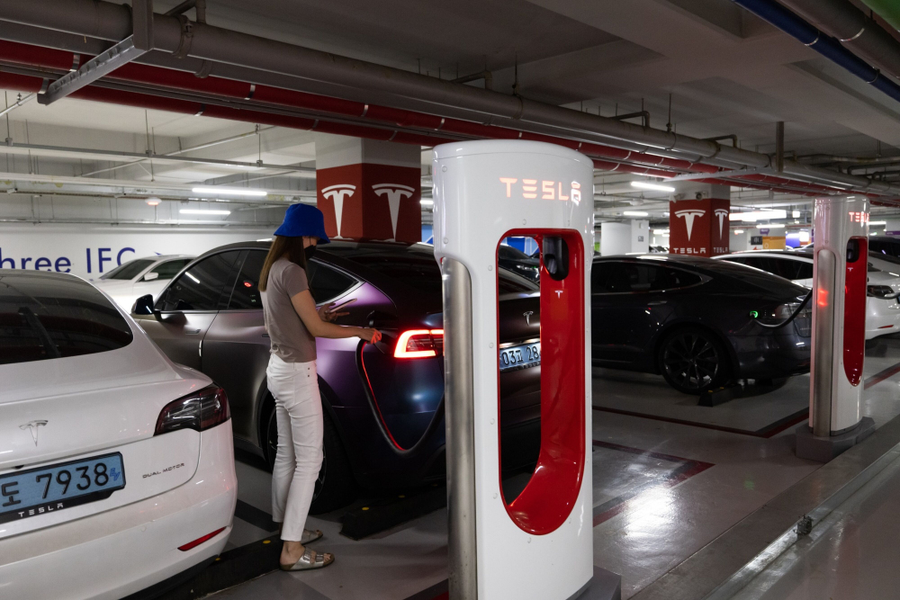 Warga mengisi daya mobil listrik di Tesla Supercharger Station, Seoul, Korea Selatan pada Minggu (7/8/2022). - Bloomberg/SeongJoon Cho