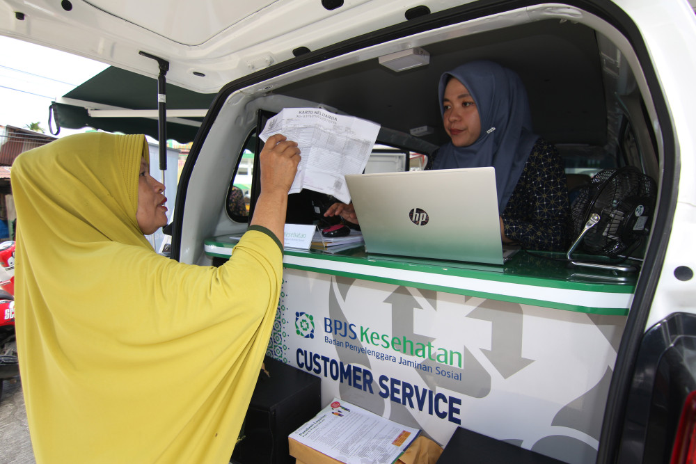 Petugas customer service BPJS Kesehatan saat melayani warga melalui layanan Mobile Customer Service di Pasar Belimbing, Kota Padang, Sumatra Barat, Selasa (5/7/2022). Bisnis/Muhammad Noli Hendra