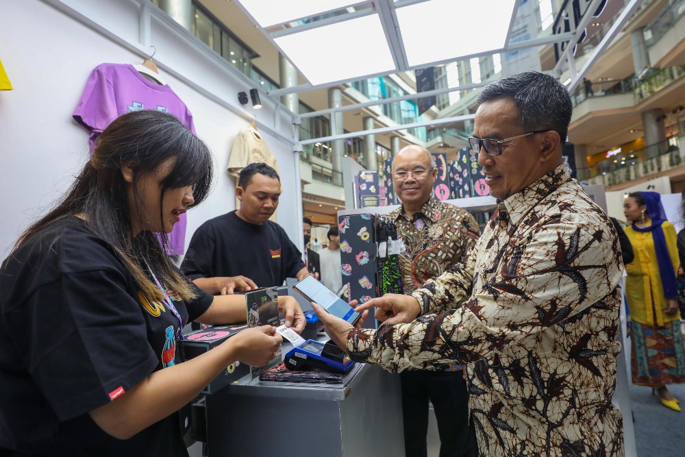 Direktur Jenderal Perdagangan Dalam Negeri Kemendag Isy Karim (kanan) didampingi Ketua Umum DPP Asosiasi Pengelola Pusat Belanja Indonesia (APPBI) Alphonzus Wijaja (kedua kanan) membayar menggunakan QRIS di salah satu stan dalam Indonesia Shopping Festival (ISF) di PIK Avenue, Jakarta, Kamis (8/8/2024)/Bisnis/Himawan L Nugraha