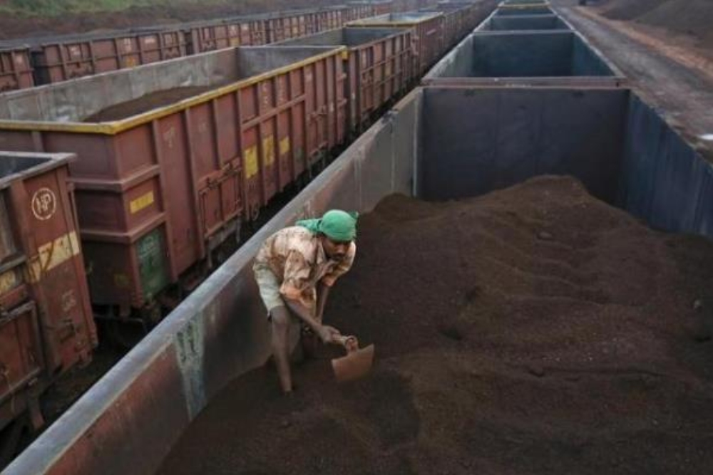 Seorang pekerja sedang meratakan bijih besi di atas kereta cargo di stasiun kereta Chitradurga, di Karnataka, India/Reuters-Danish Siddiqui