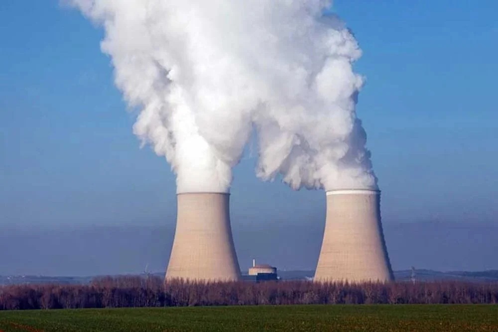 Menara pendingin melepaskan uap air di dekat lahan pertanian di pembangkit listrik tenaga nuklir Nogent yang dioperasikan oleh Electricite de France SA (EDF), di Nogent-sur-Seine, Prancis, Selasa (21/12/2021). Bloomberg/Cyril Marcilhacy